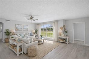 A bright living room features light wood-look flooring, a large arched window, and neutral furniture — 2064 Atlantic Boulevard, Vero Beach FL 32960, VERO BEACH, FL