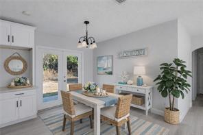 A dining room with a white table, woven chairs, a chandelier, and a side console — 2064 Atlantic Boulevard, Vero Beach FL 32960, VERO BEACH, FL