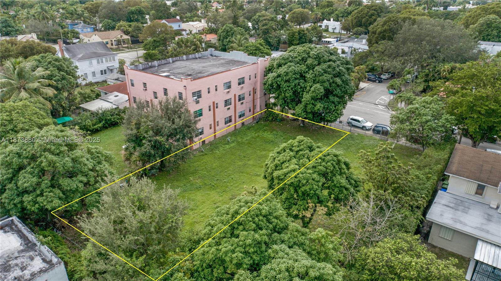 An aerial view shows a vacant, rectangular grassy lot outlined in yellow next to an apartment building — 1001 SW 15th Ave, Miami FL 33135, MIAMI, FL