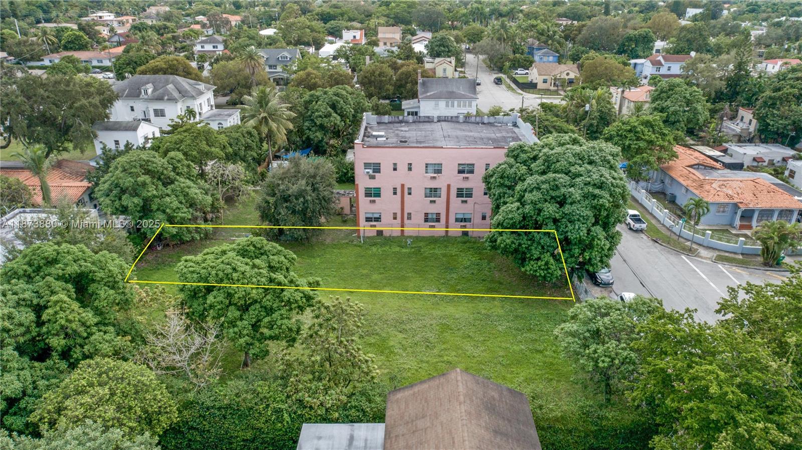 An aerial view shows a vacant rectangular lot outlined in yellow next to a pink building — 1001 SW 15th Ave, Miami FL 33135, MIAMI, FL