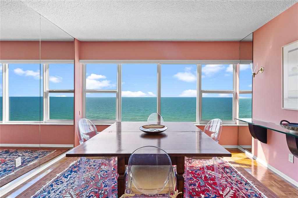 A dining room with a wooden table, clear chairs, a patterned rug, and ocean views — 601 LONGBOAT CLUB ROAD UNIT 902S, LONGBOAT KEY, FL