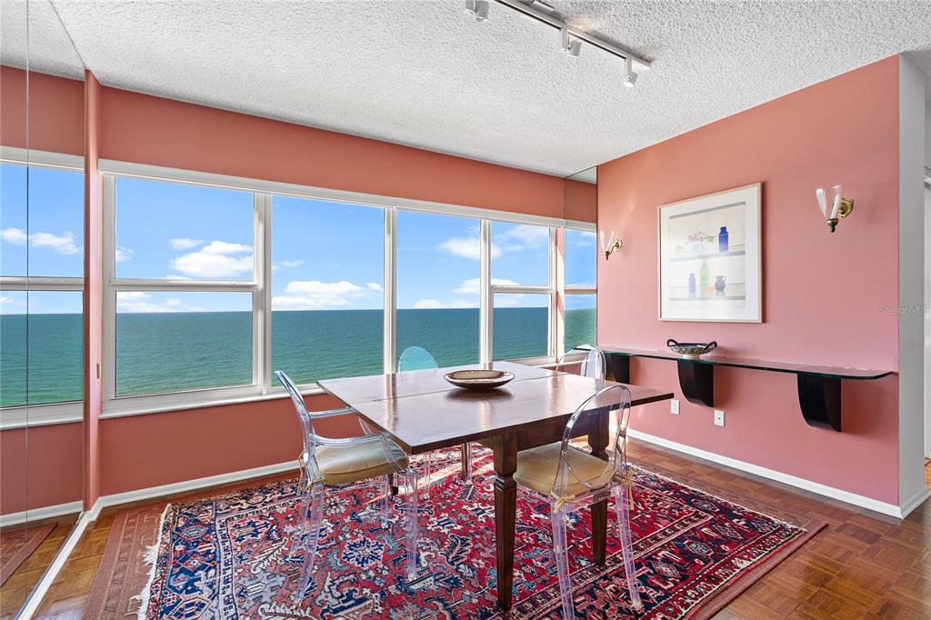 A dining room with a wooden table, clear chairs, a patterned rug, and ocean views — 601 LONGBOAT CLUB ROAD UNIT 902S, LONGBOAT KEY, FL