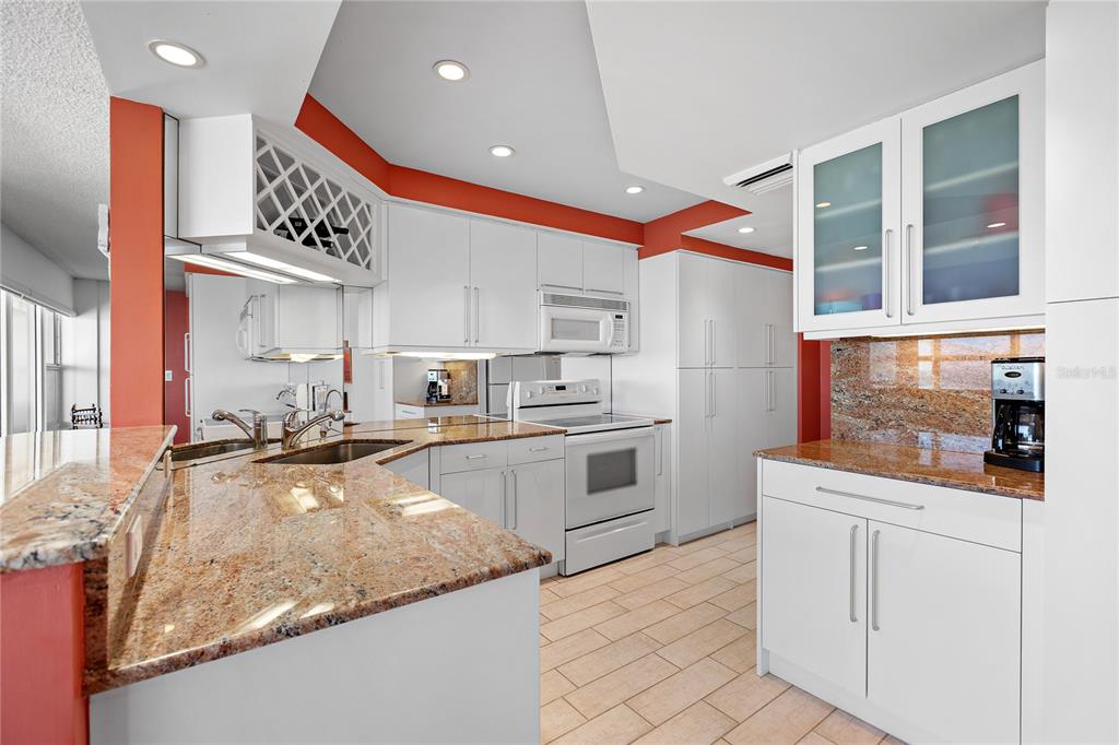 A kitchen features white cabinetry, granite countertops, and a wine rack above the sink — 601 LONGBOAT CLUB ROAD UNIT 902S, LONGBOAT KEY, FL