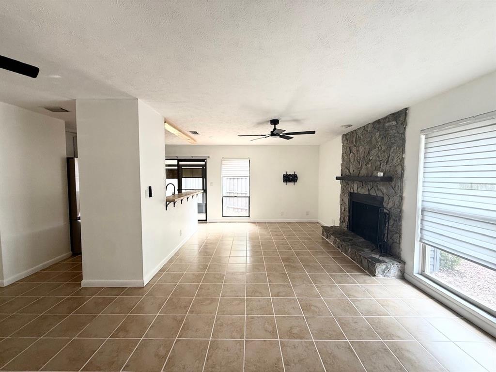 A living room features a stone fireplace, tiled floors, and a ceiling fan — 1819 SW 29TH TERRACE, OCALA, FL