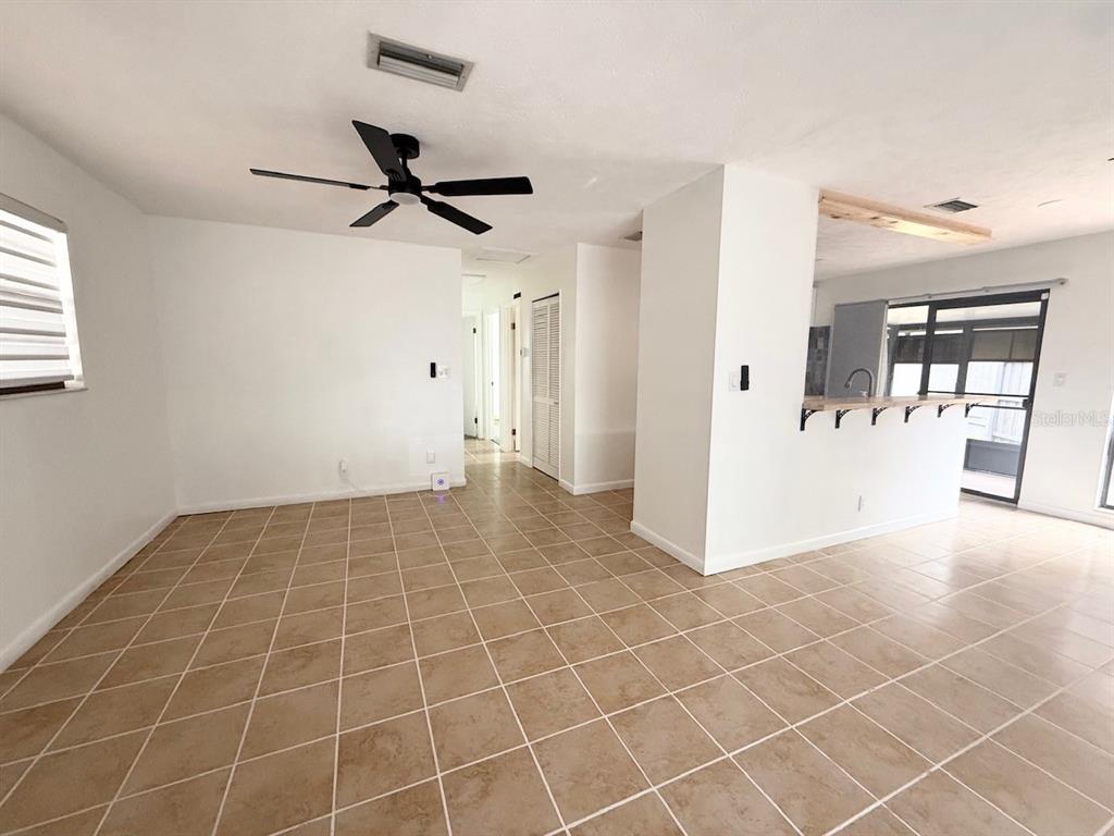 An open-concept living area features light-colored tile flooring, white walls, and a ceiling fan — 1819 SW 29TH TERRACE, OCALA, FL