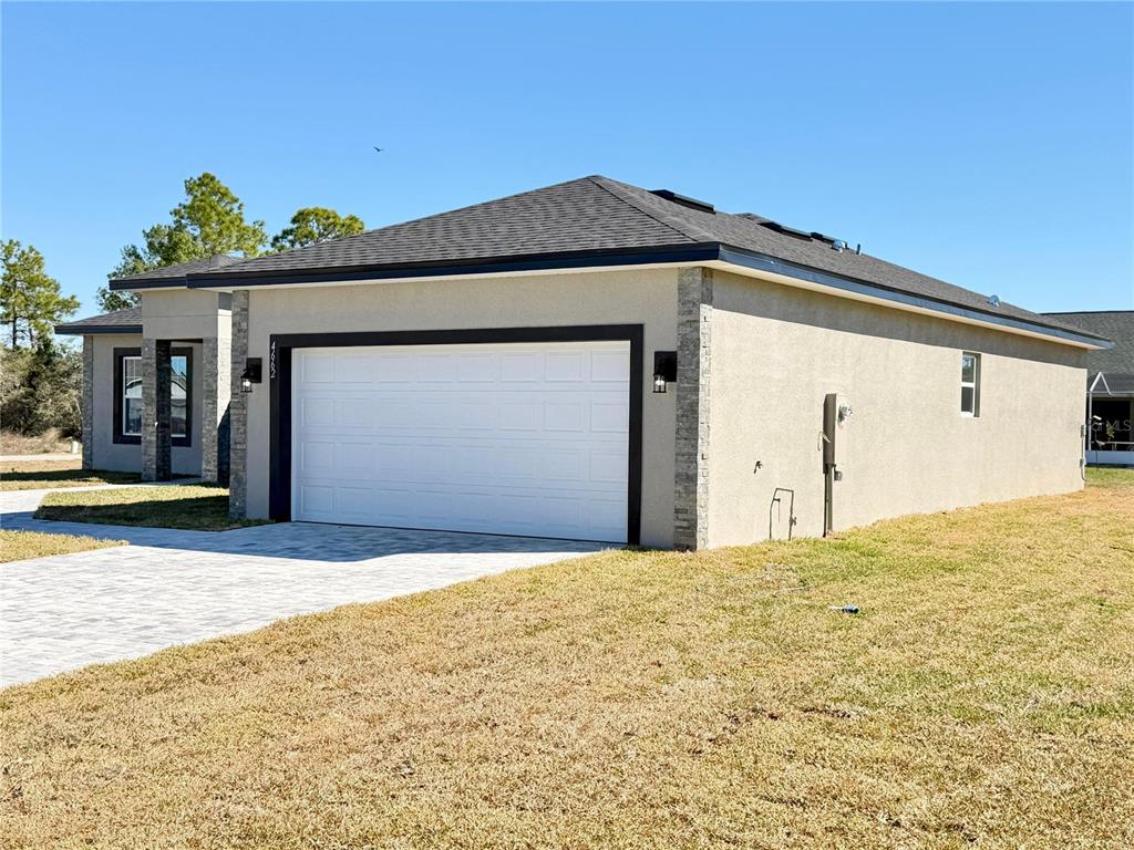 A tan stucco house with a white garage door and a stone-accented entryway — 4662 SAN IGNACIO DRIVE, SEBRING, FL
