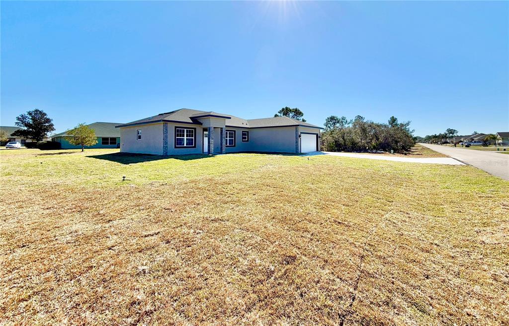 A single-story house with a gray exterior, a two-car garage, and a large grassy yard — 4662 SAN IGNACIO DRIVE, SEBRING, FL