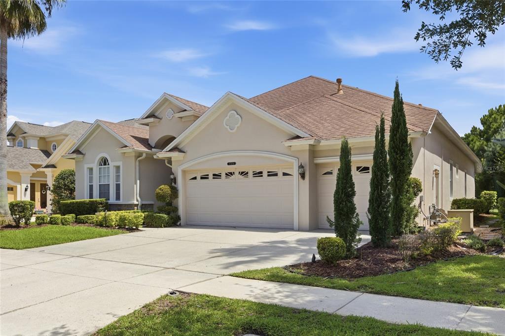 A beige single-story house with a three-car garage and a landscaped front yard — 8309 OLD TOWN DRIVE, TAMPA, FL