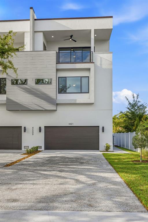 The exterior of a modern multi-story townhouse features a gray garage door and balcony — 4509 W NORTH A STREET UNIT 1, TAMPA, FL