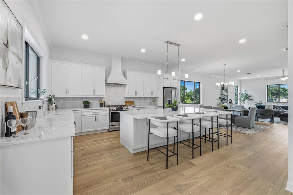 A modern white kitchen features a large island with bar seating and light wood floors — 4509 W NORTH A STREET UNIT 1, TAMPA, FL