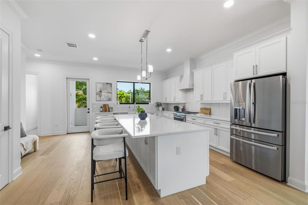 A modern white kitchen features a large center island with bar seating and stainless appliances — 4509 W NORTH A STREET UNIT 1, TAMPA, FL