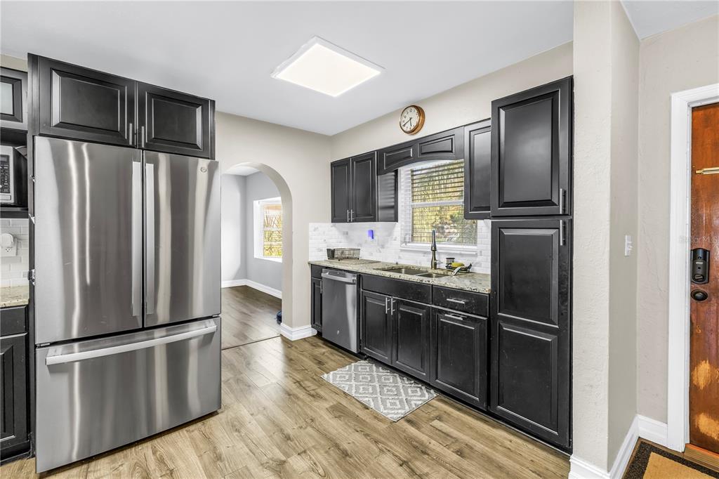 A kitchen with dark cabinets, stainless steel appliances, light countertops, and wood-look flooring — 4708 W COACHMAN AVENUE, TAMPA, FL