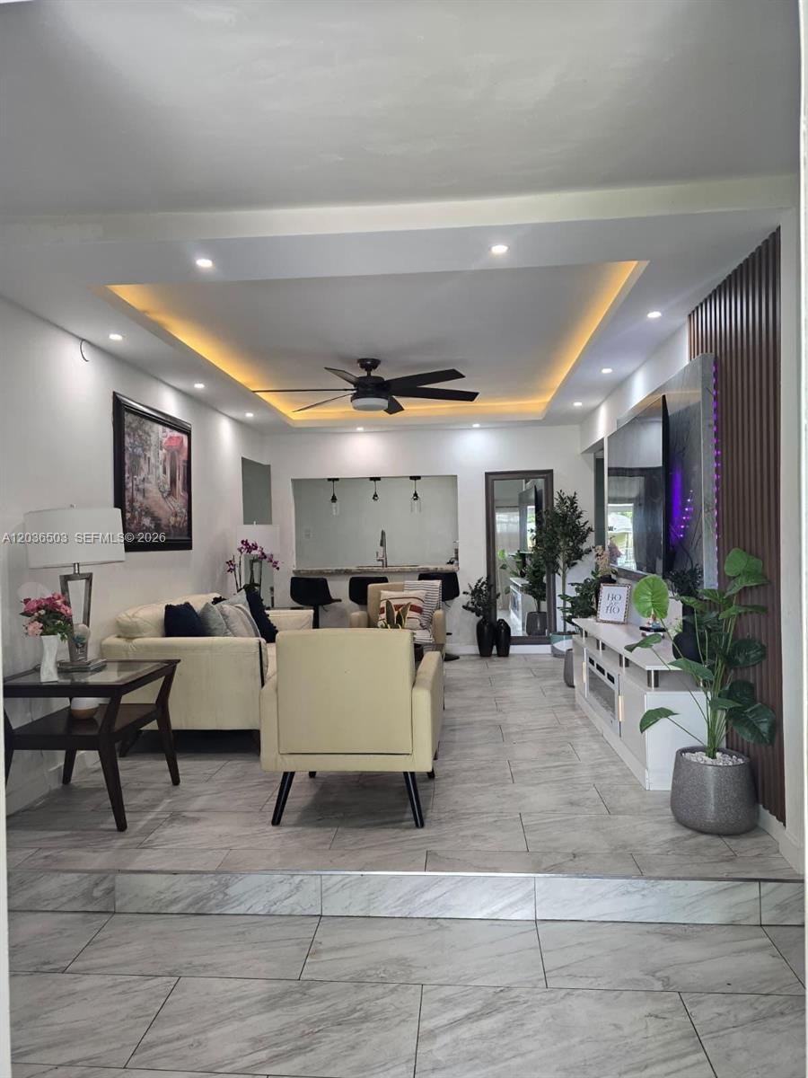 A living room features a tray ceiling with recessed lighting, tile flooring, and a media wall — 1055 NW 58th Ter, Miami FL 33127, MIAMI, FL