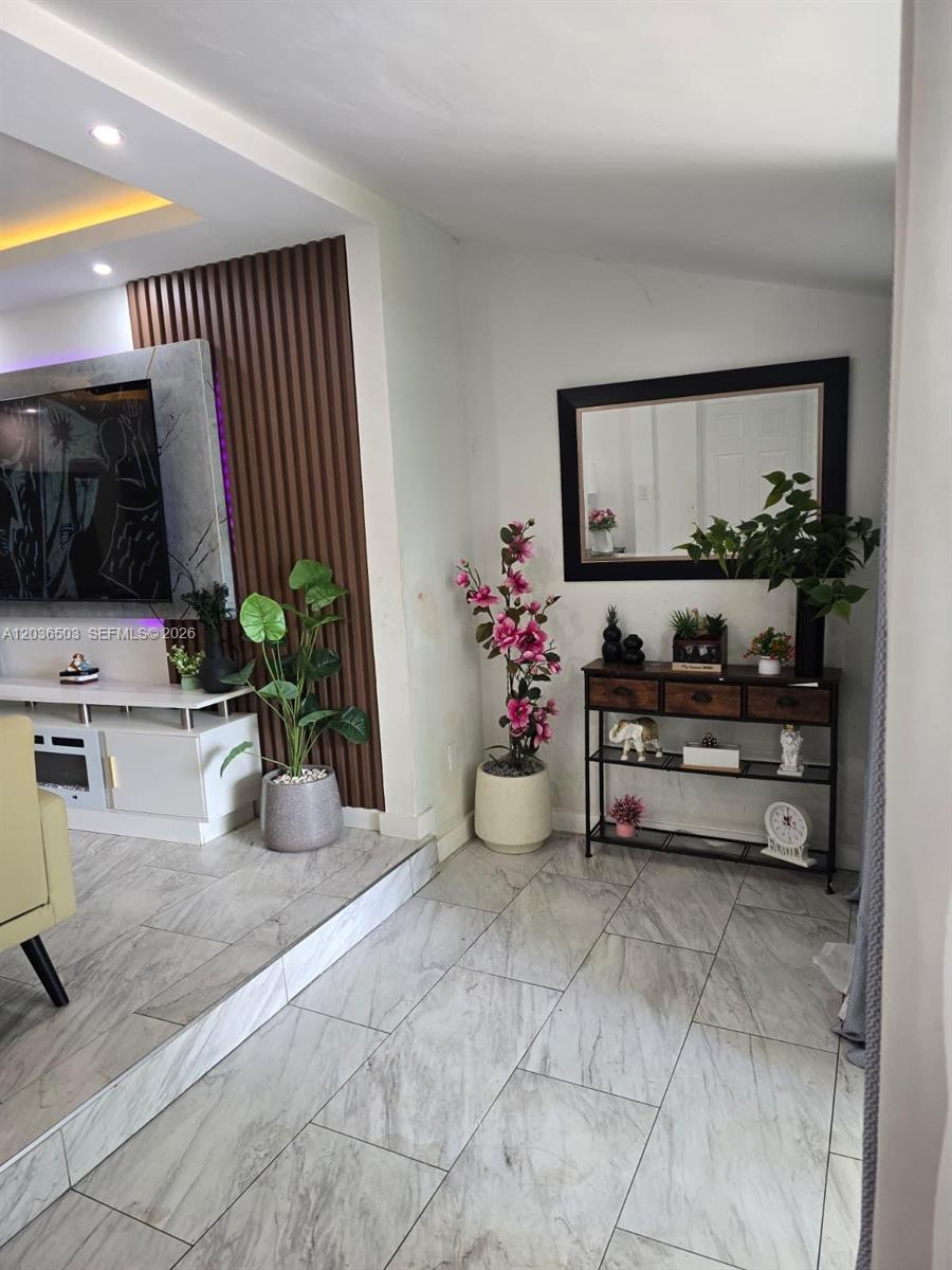 A living room features a tiled floor, a wood-slatted accent wall, and a console table — 1055 NW 58th Ter, Miami FL 33127, MIAMI, FL