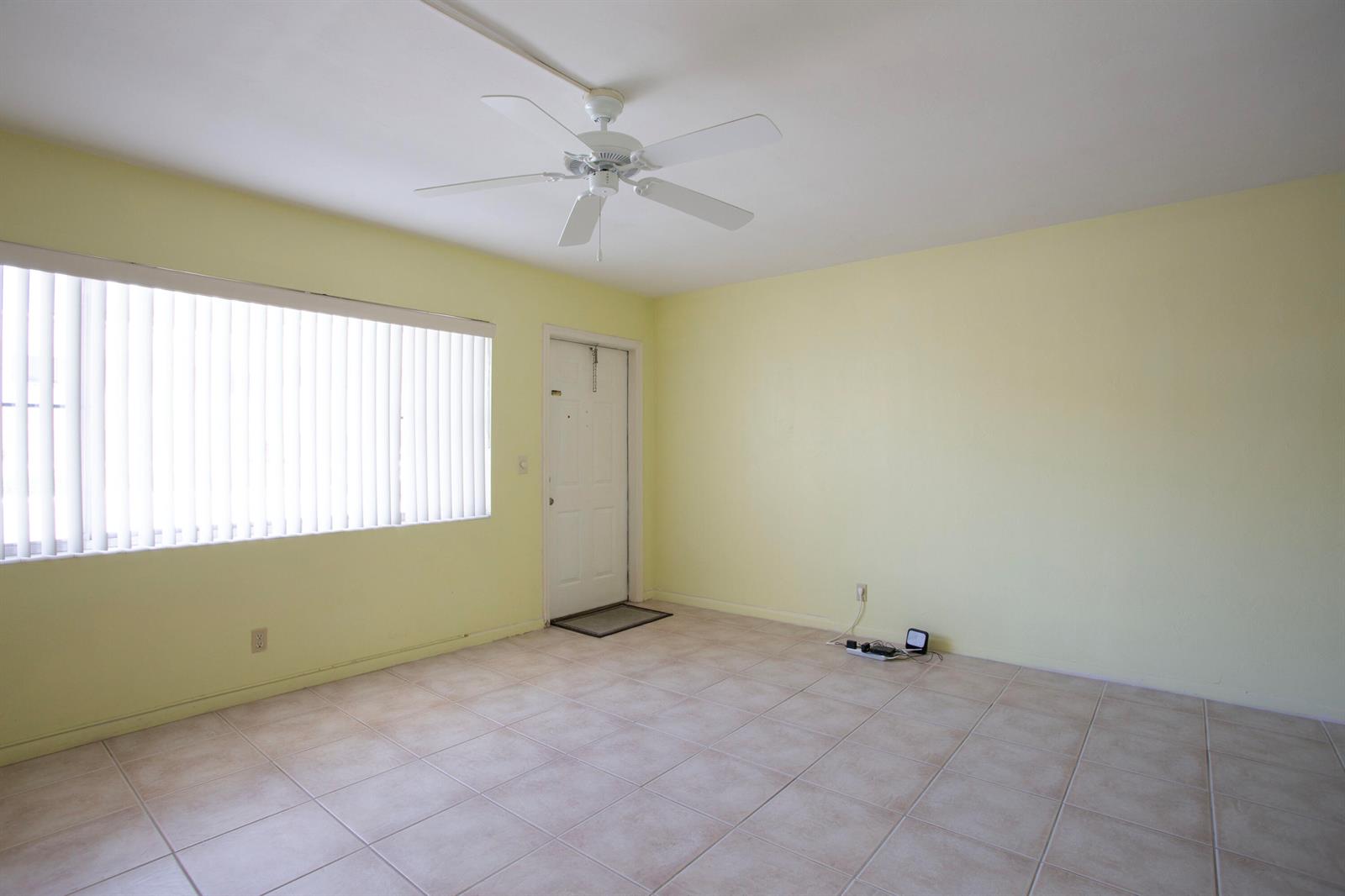 An empty room features pale yellow walls, light-colored tile flooring, and a white ceiling fan — 3160 Lake Osborne Drive # 108, FL 33461, FL