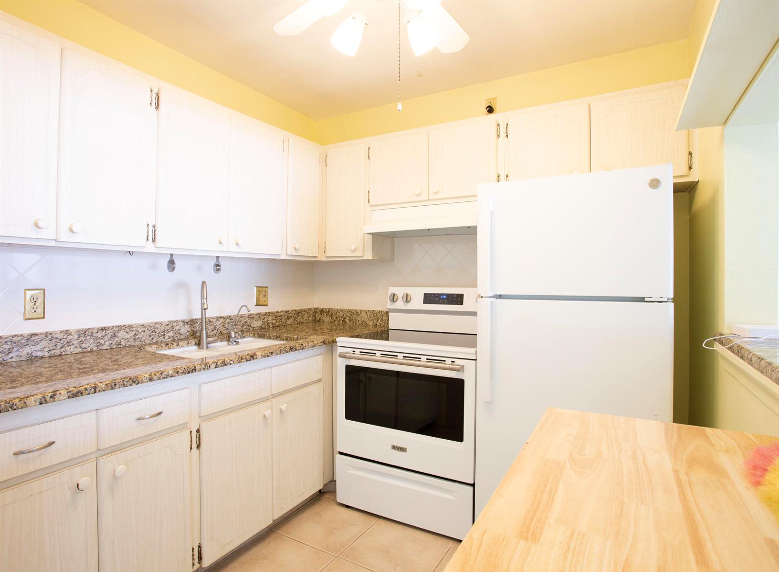 A kitchen features white cabinets, granite countertops, a white stove, and a white refrigerator — 3160 Lake Osborne Drive # 108, FL 33461, FL