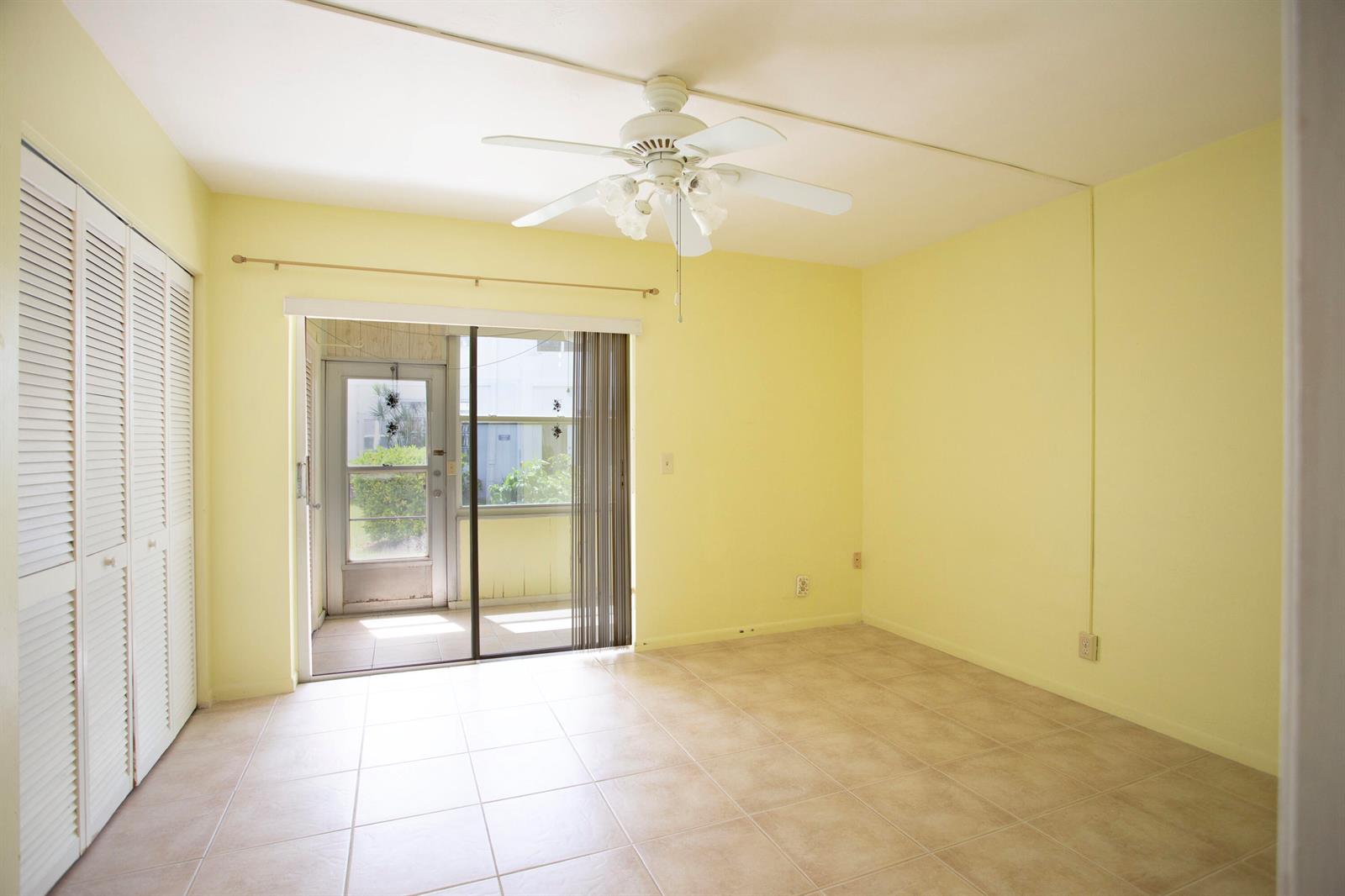 A room with yellow walls, tile flooring, a ceiling fan, and a sliding glass door — 3160 Lake Osborne Drive # 108, FL 33461, FL