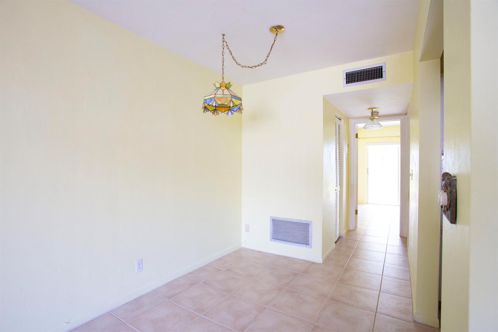 A room with light yellow walls, tile flooring, a stained-glass pendant light, and a hallway — 3160 Lake Osborne Drive # 108, FL 33461, FL