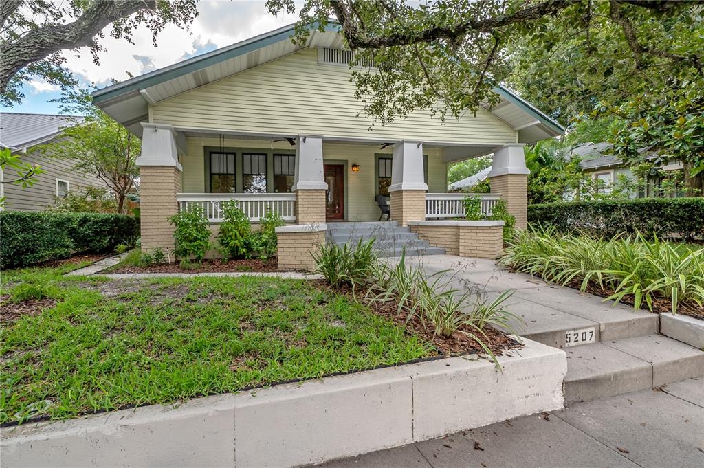 A light yellow bungalow with a brick-based front porch and a concrete walkway — 5207 N SUWANEE AVENUE, TAMPA, FL
