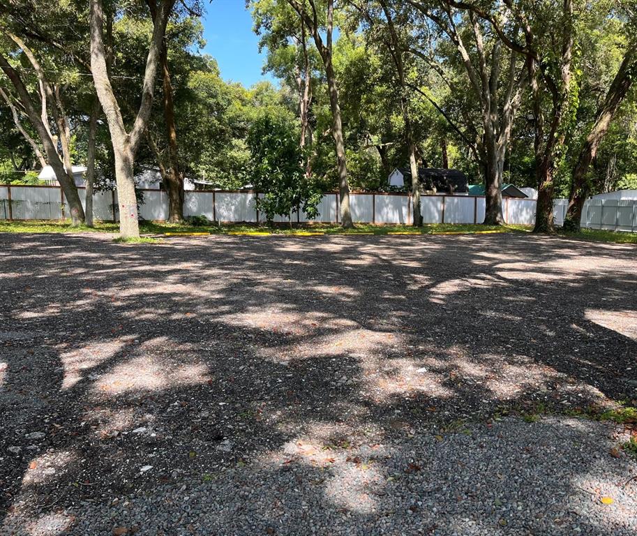 A gravel parking lot is bordered by a white fence and mature trees — 10516 579 HIGHWAY, THONOTOSASSA, FL