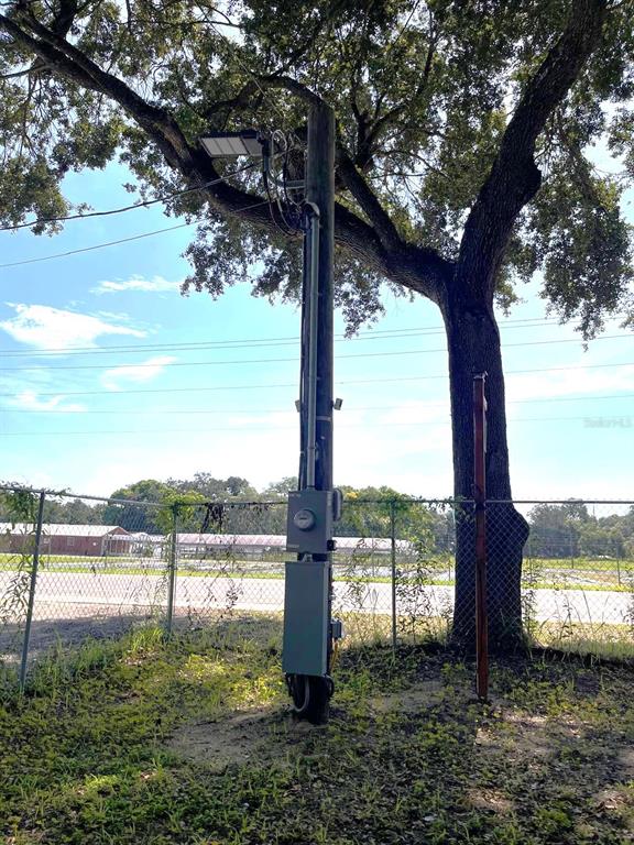A utility pole with an electrical meter and light fixture stands in a grassy area — 10516 579 HIGHWAY, THONOTOSASSA, FL