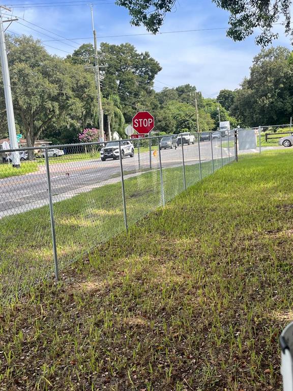 A chain-link fence borders a grassy yard next to a road with a stop sign — 10516 579 HIGHWAY, THONOTOSASSA, FL