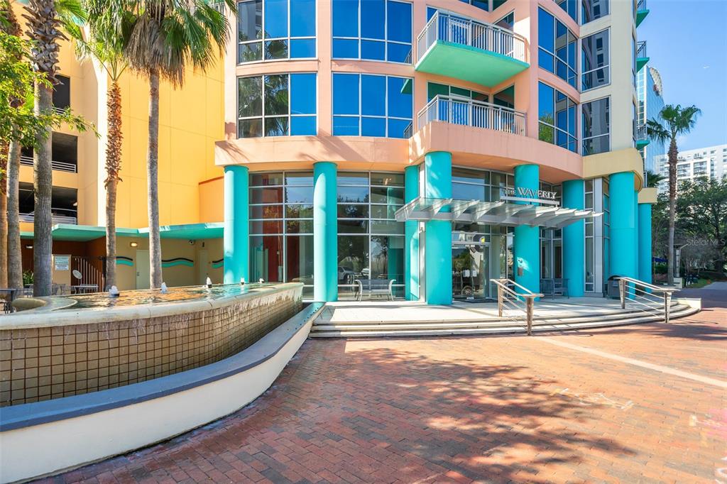 The exterior of a multi-story building features a fountain, palm trees, and a turquoise entrance — 322 E CENTRAL BOULEVARD UNIT 1602, ORLANDO, FL
