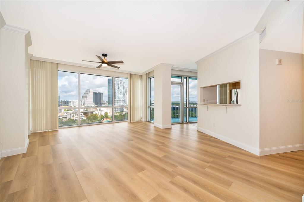 An empty living room with light wood flooring, a ceiling fan, and floor-to-ceiling city views — 322 E CENTRAL BOULEVARD UNIT 1602, ORLANDO, FL