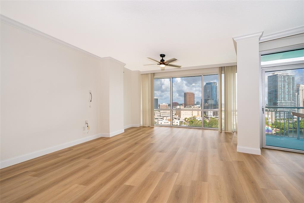 An empty living room features light wood-look flooring, a ceiling fan, and floor-to-ceiling city views — 322 E CENTRAL BOULEVARD UNIT 1602, ORLANDO, FL