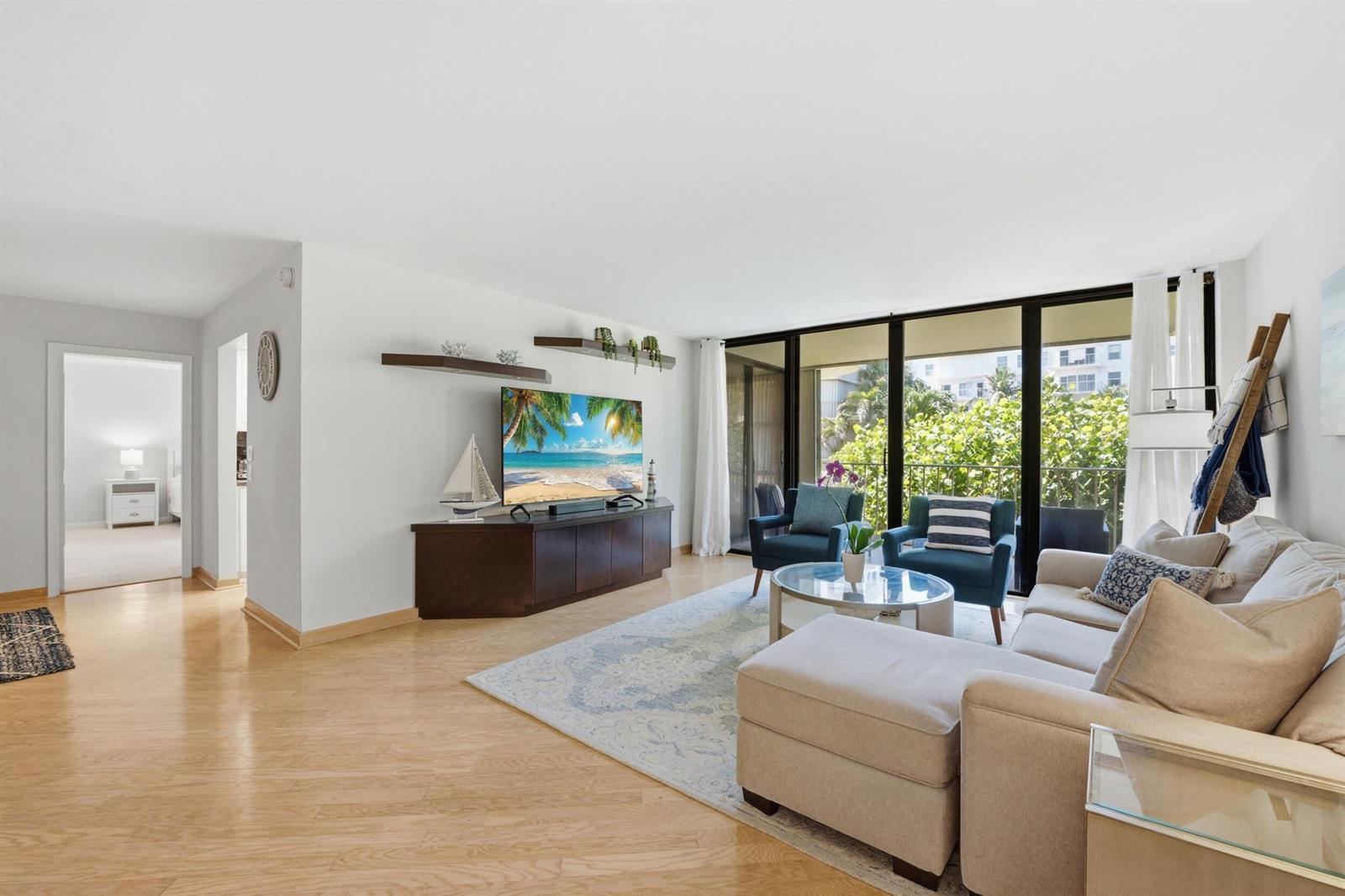 A living room features a sectional sofa, two blue armchairs, and a television on console — 3200 S Ocean Boulevard # D203, Palm Beach FL 33480, PALM BEACH, FL