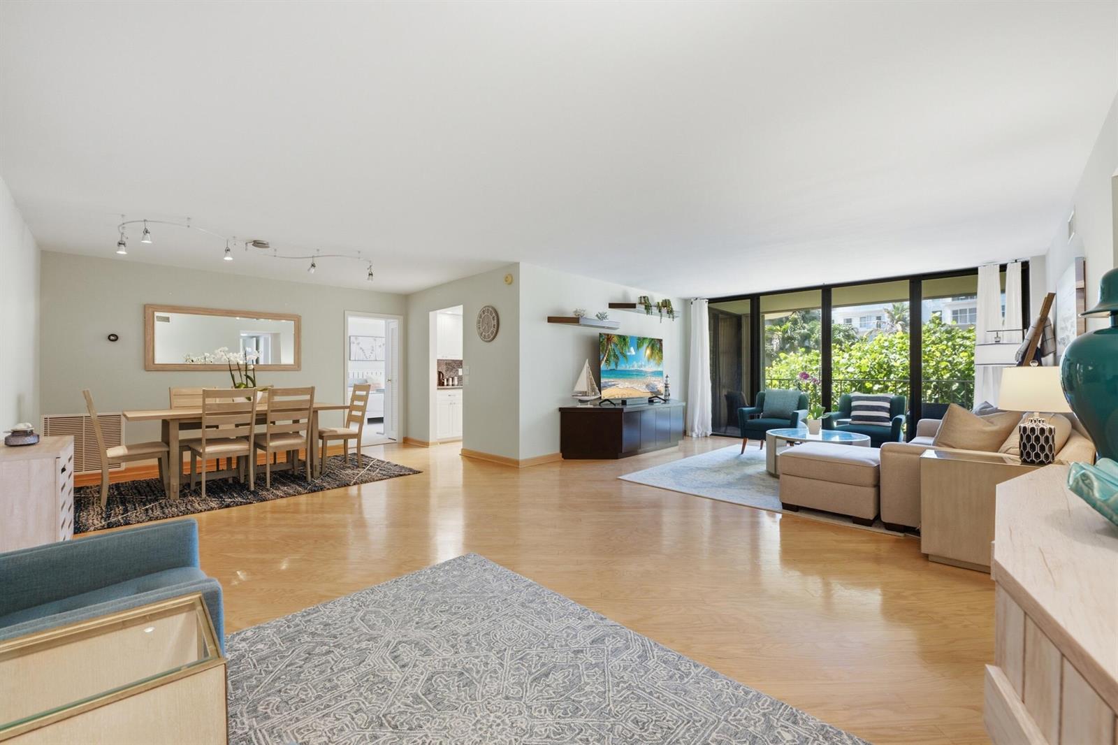 An open-concept living and dining area features light hardwood floors, neutral walls, and floor-to-ceiling windows — 3200 S Ocean Boulevard # D203, Palm Beach FL 33480, PALM BEACH, FL