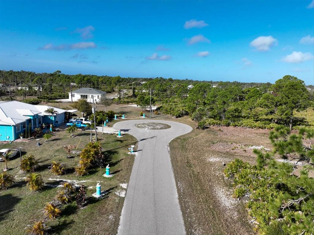 An aerial view shows a paved cul-de-sac surrounded by undeveloped land and a nearby house — 6 BERTH COURT, PLACIDA, FL