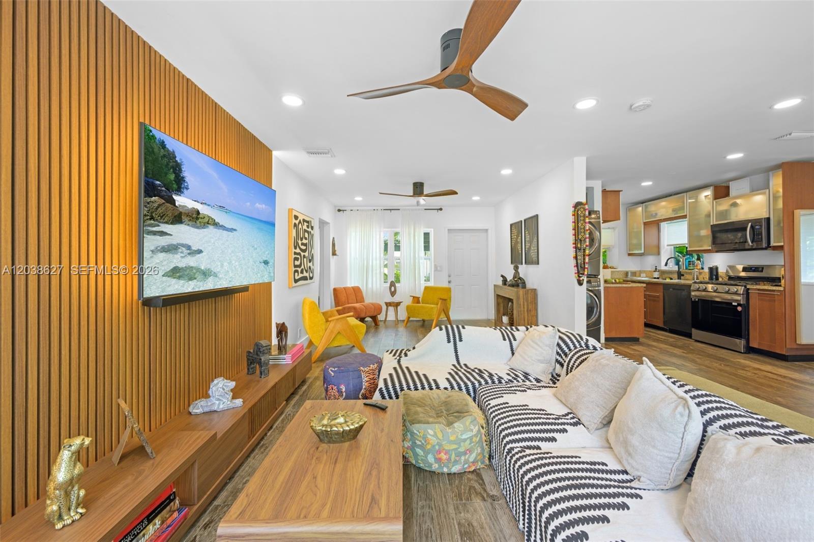 A living room with a slatted wood accent wall, television, and an open-concept kitchen — 761 NE 82nd Ter, Miami FL 33138, MIAMI, FL