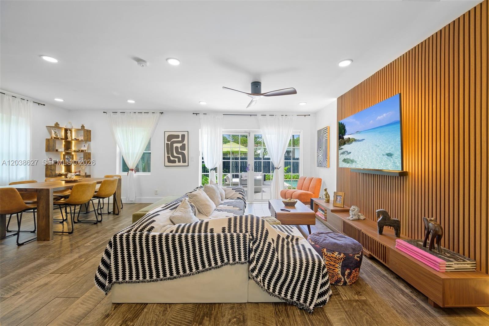 A living and dining area features a slatted wood accent wall, television, and sectional sofa — 761 NE 82nd Ter, Miami FL 33138, MIAMI, FL