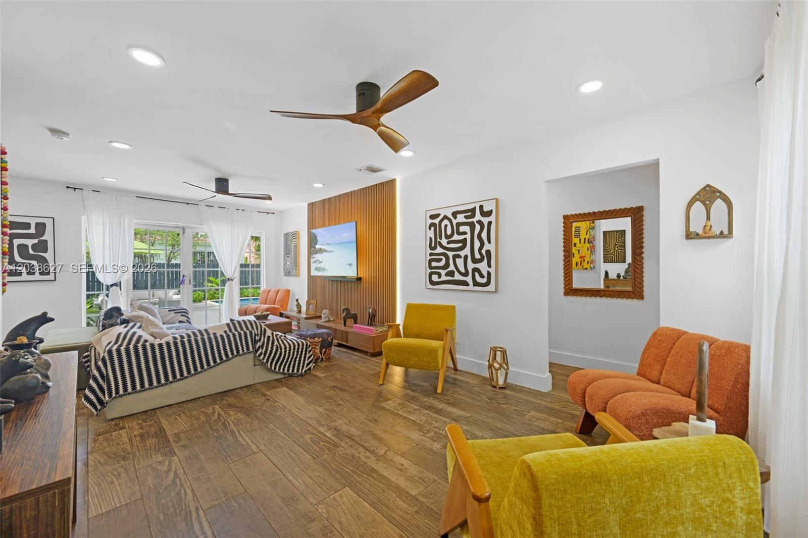 A living room features wood-look tile flooring, a slatted wood accent wall, and colorful furniture — 761 NE 82nd Ter, Miami FL 33138, MIAMI, FL