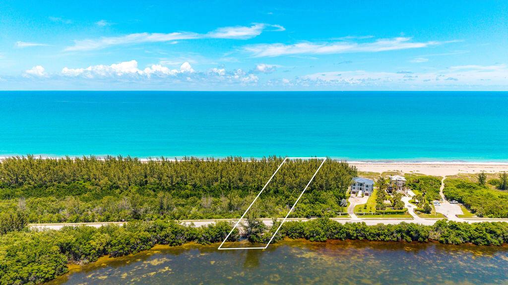 An aerial view shows two houses nestled among trees along a sandy beach and ocean — 0 S Ocean Drive, Fort Pierce FL, FORT PIERCE, FL