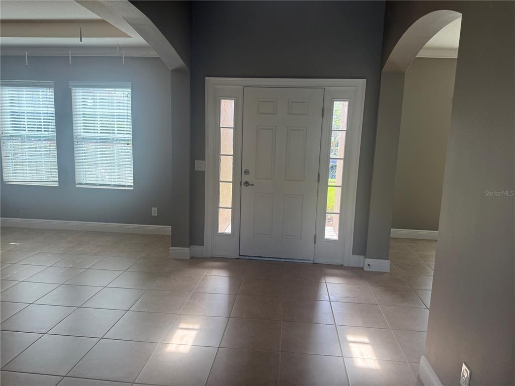 An entryway features a white front door with sidelights, tile flooring, and arched wall openings — 3128 AMALFI DRIVE, ORLANDO, FL