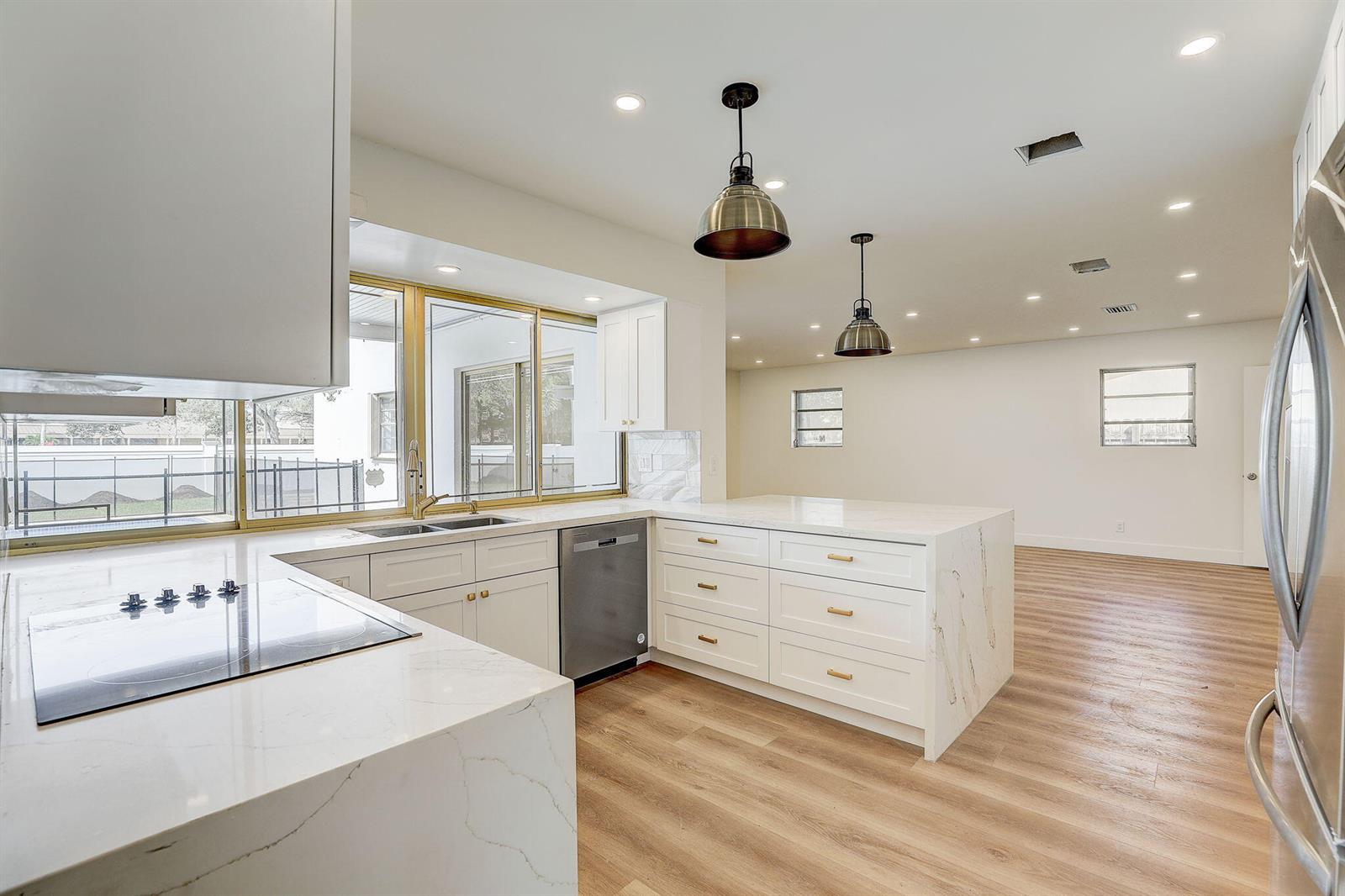 A modern kitchen features white cabinets, marble countertops, gold hardware, and stainless steel appliances — 3900 N 45th Avenue, Hollywood FL 33021, HOLLYWOOD, FL