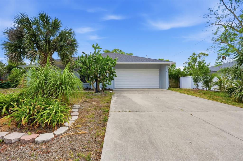 A single-story house with a white garage door, a concrete driveway, and a cactus plant — 1163 RINGTAIL ROAD, VENICE, FL