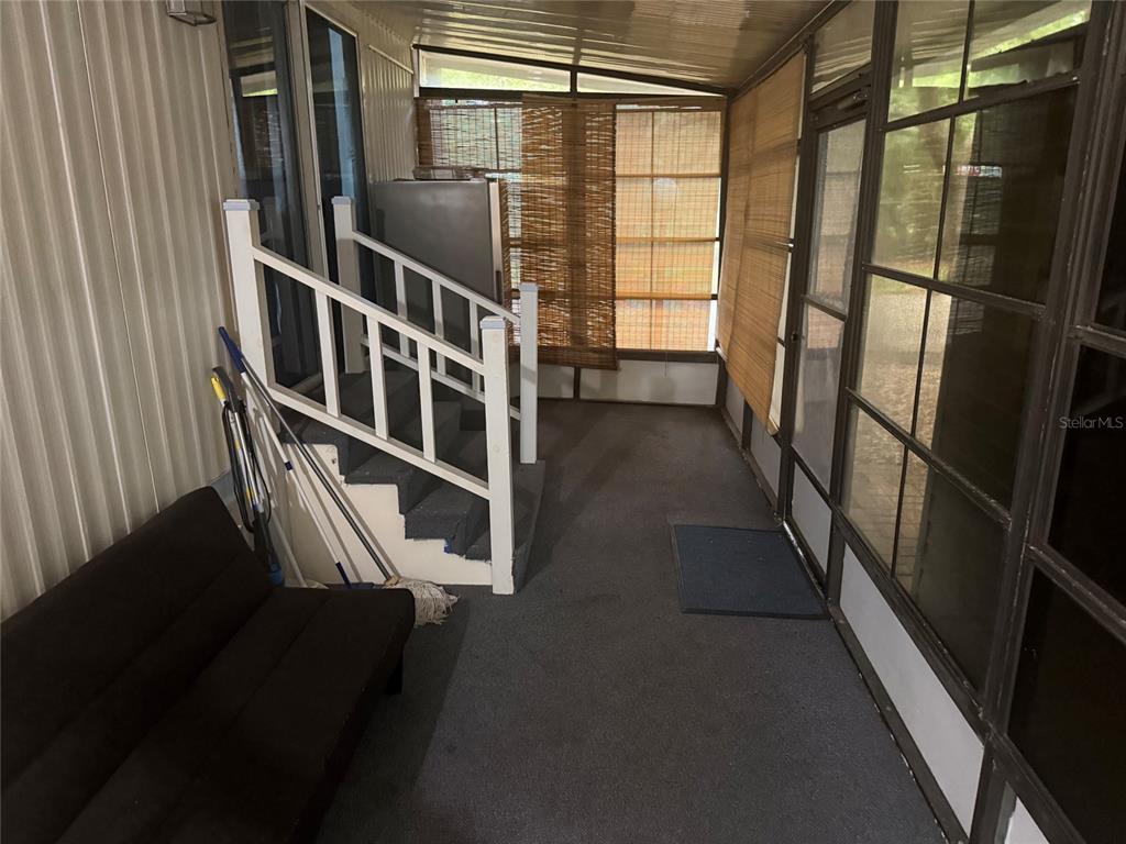 A screened-in porch features gray carpeting, a white staircase, and a dark futon — 3000 CLARCONA ROAD UNIT 2715, APOPKA, FL