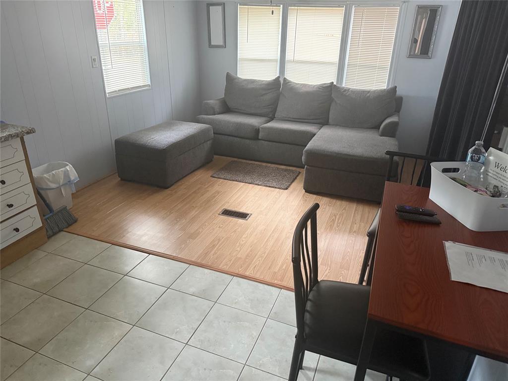 A living room with light wood flooring, a gray sectional sofa, and a tile-floored kitchen — 3000 CLARCONA ROAD UNIT 2715, APOPKA, FL