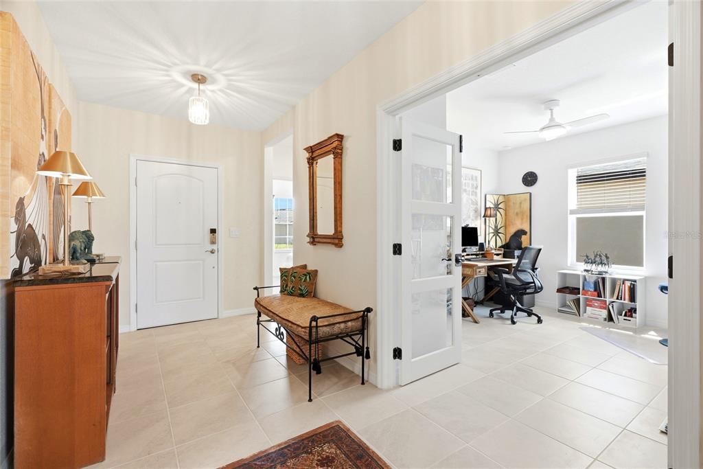 An open-concept living and dining area features two brown leather sofas and a white kitchen — 9860 LAST LIGHT GLEN, PARRISH, FL