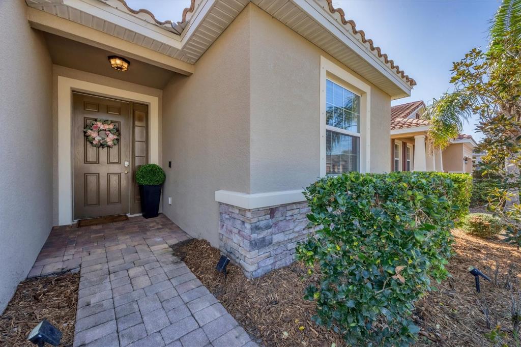 The exterior of a house features a paved walkway leading to a brown front door — 5333 CHARLIE BROWN LANE, SARASOTA, FL
