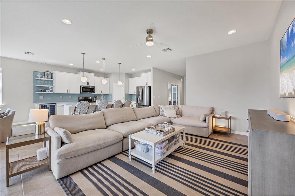 A living room with a large sectional sofa, striped rug, and an open-concept kitchen — 5333 CHARLIE BROWN LANE, SARASOTA, FL