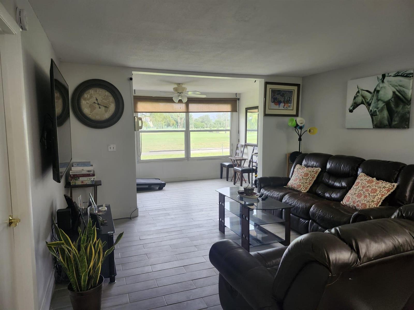 A living room with tile floors, leather sofas, a glass coffee table, and a sunroom view — 7684 NW 18th Street # 101, Margate FL 33063, MARGATE, FL