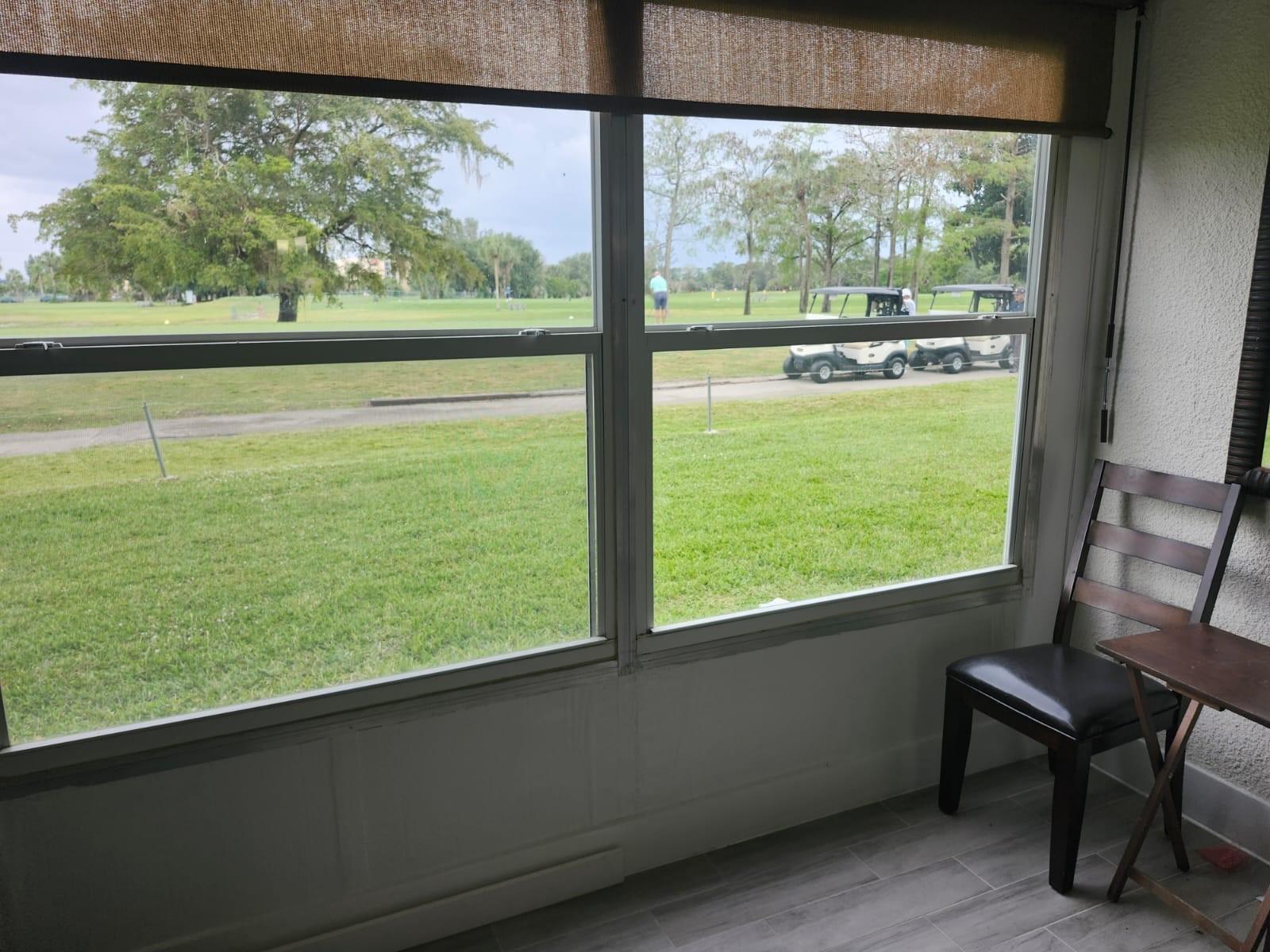 A sunroom with a view of a golf course, featuring a chair and a small table — 7684 NW 18th Street # 101, Margate FL 33063, MARGATE, FL