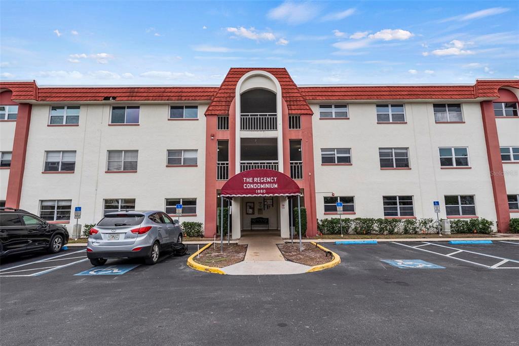 The exterior of a three-story condominium building features a red-tiled roof and a covered entrance — 1860 MASSACHUSETTS AVENUE NE UNIT 206, ST PETERSBURG, FL