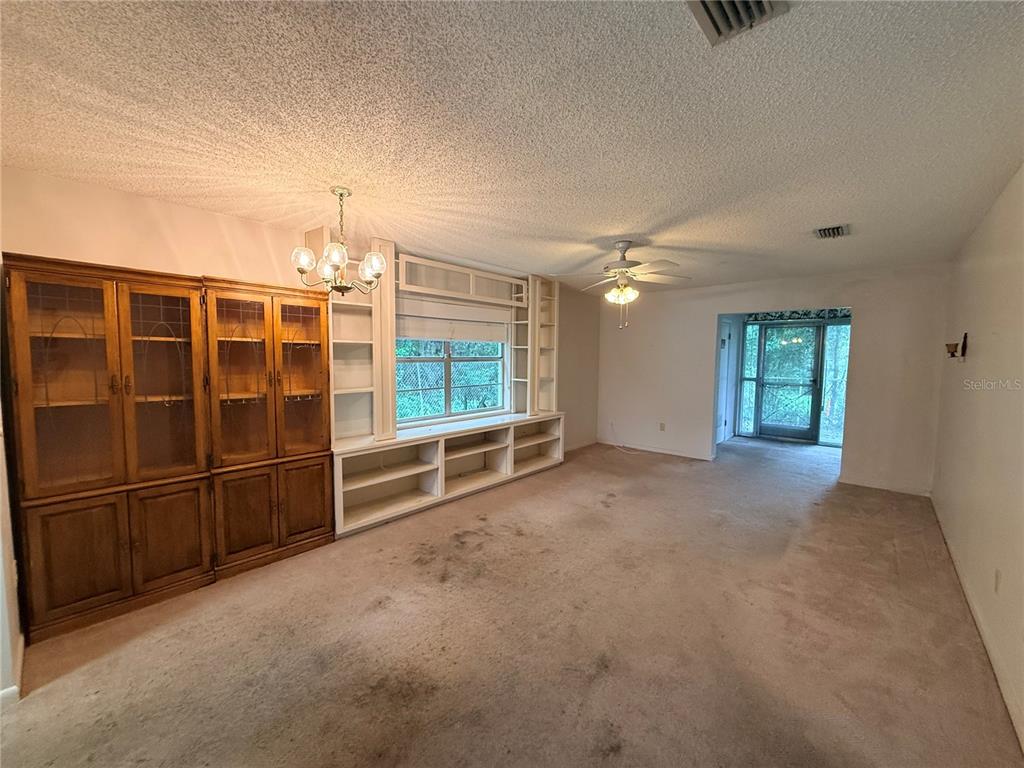 A living room features beige carpeting, a built-in wooden hutch, and white shelving units — 155 N HILL AVENUE UNIT 80, DELAND, FL