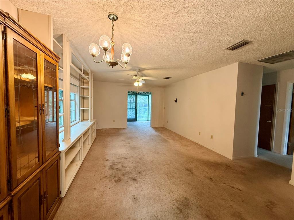 A living room features a large wooden hutch, built-in shelving, carpeted floors, and a chandelier — 155 N HILL AVENUE UNIT 80, DELAND, FL