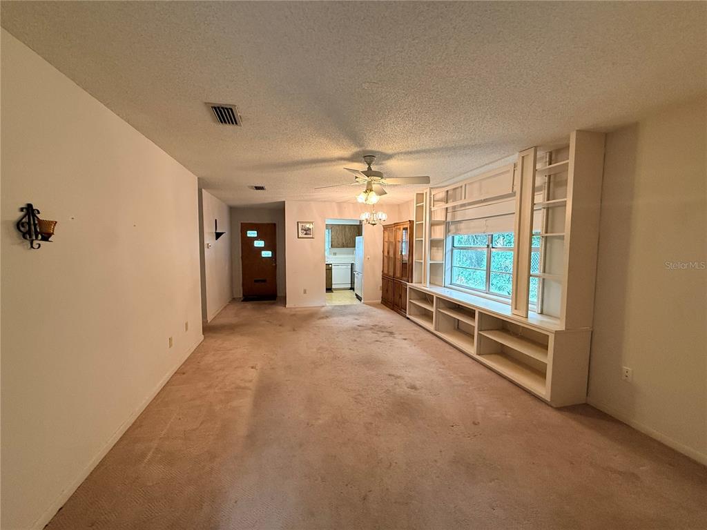 A living room features beige carpeting, a ceiling fan, and built-in white shelving — 155 N HILL AVENUE UNIT 80, DELAND, FL